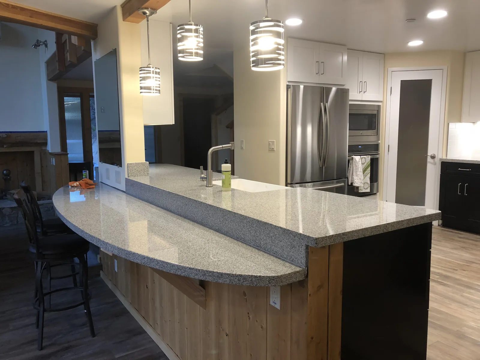 Curved kitchen island and raised bar with a polished light speckled countertop
