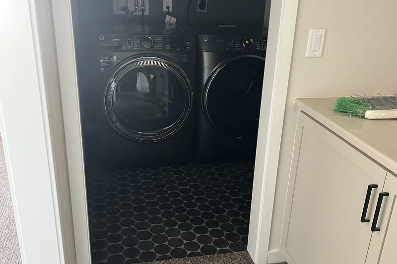 Black circle mosaic tile flooring in a laundry closet with washer and dryer, installed by My-Key Tile & Flooring