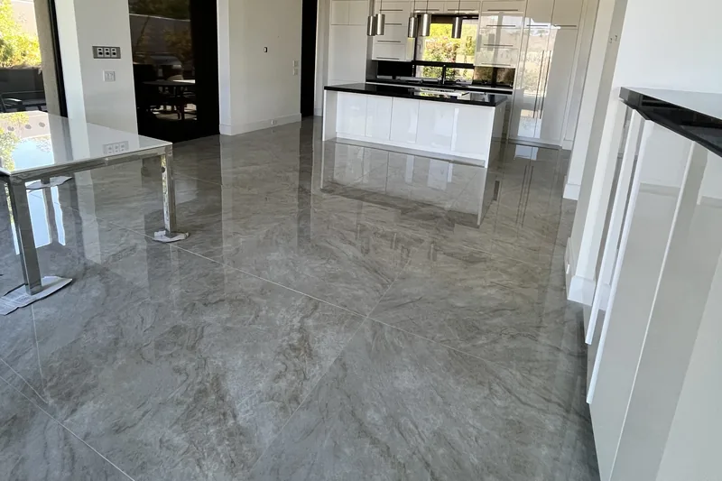 Taj Mahal-look porcelain tile flooring installed through a modern white kitchen with black countertops, Palm Desert